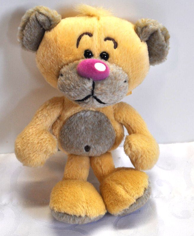 Knuffel van geel en grijs pluche, met grote voeten, roze neus en rode tong, zittende positie.